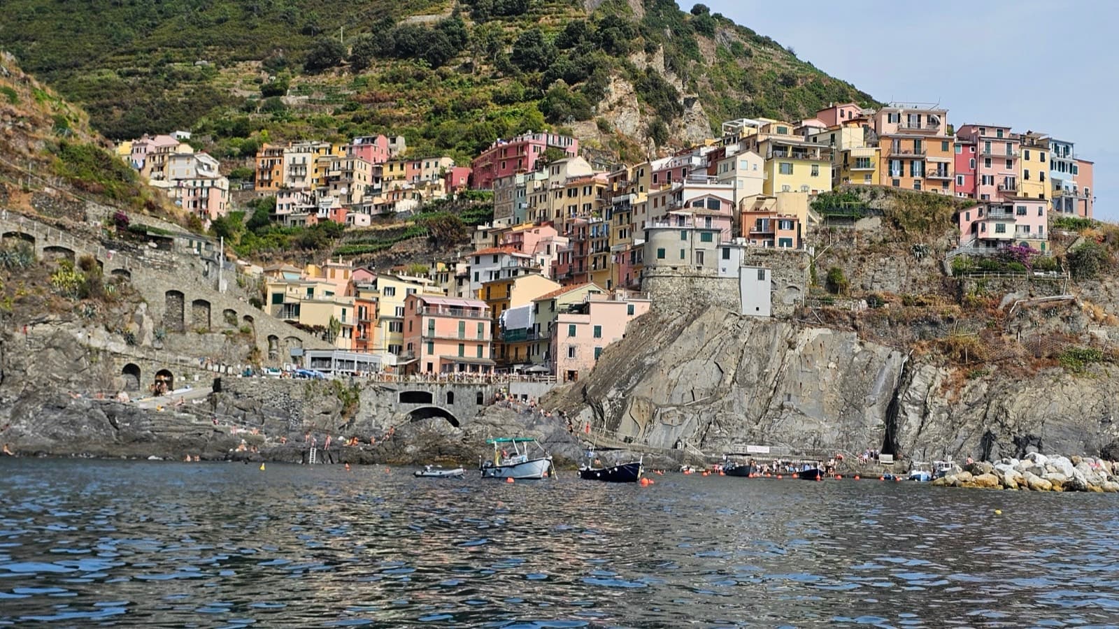 Pastel houses stacked on a cliff above a harbor